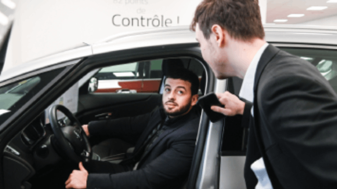 Photographie d'un vendeur conseillant un client à l'intérieur d'un véhicule.