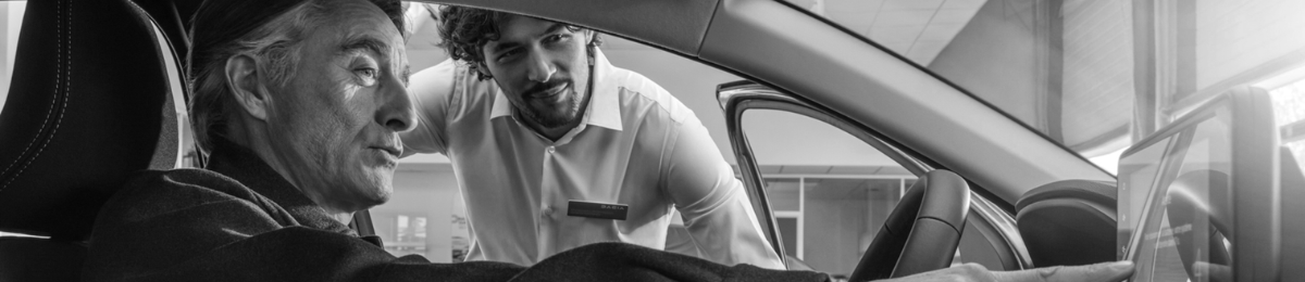 Photographie d'un vendeur et d'une cliente échangeant sur un véhicule.